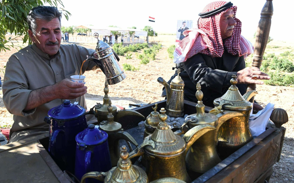 two arab men brewing and pouring coffee