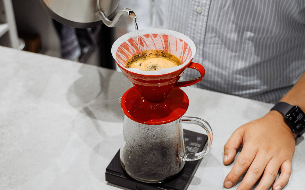 A barista brews coffee with a V60.