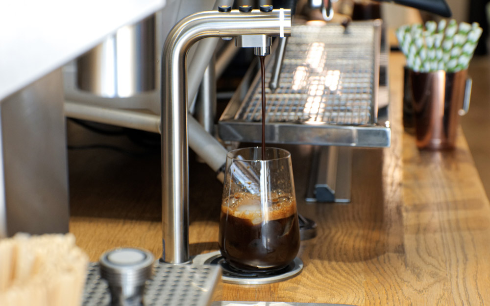 A Marco POUR'D font dispenses coffee concentrate into a glass with ice.